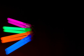 Colorful fluorescent light neon big glow stick on mirror reflection black background