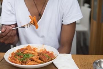 Man eating pasta with forked raised