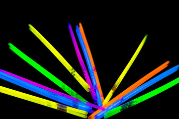 Colorful fluorescent light neon big glow stick on mirror reflection black background