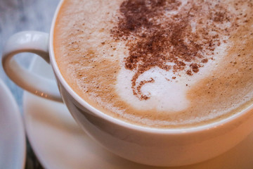 Cup of cappuccino coffee on wooden table.