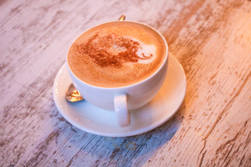 Cup of cappuccino coffee on wooden table.