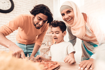 Happy Arabian Family Eating Pizza in Kitchen.
