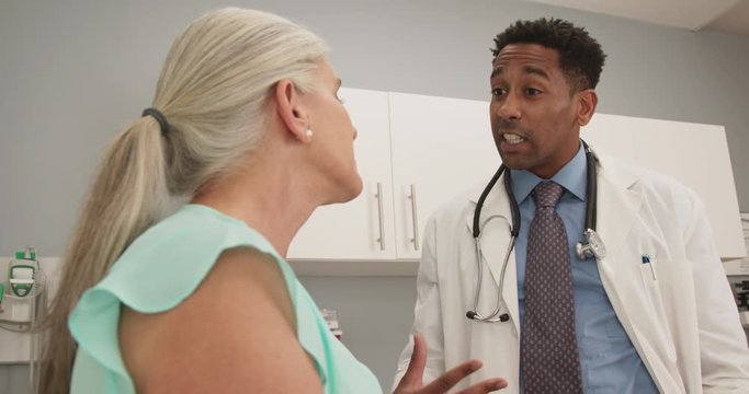Close up of elderly woman consulting with millennial doctor inside medical office. Closeup of senior woman talking to young african-american physician about health condition