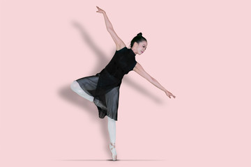 Female ballerina dancing with tiptoe poses in studio