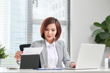 attractive businesswoman is sitting at desk with computer and calendar in the office