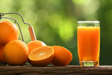 Fresh orange juice in glass with sliced orange on wood and nature background