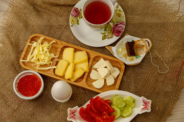 Natural breakfast consisting of cheeses, caviar, tomatoes, cucumbers, butter, eggs, rye bread and tea. The concept of tasty and natural food.
