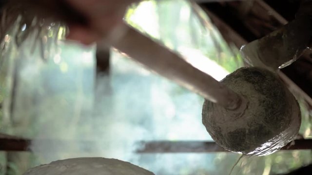 A man turns the stick over the fire, adding latex to produce the artisanal rubber that is sold in the nearest town, in the middle of the Amazon rainforest.