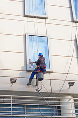 Window washer on a high building. Moscow, Russia - April 24, 2018: Man washing windows  at height