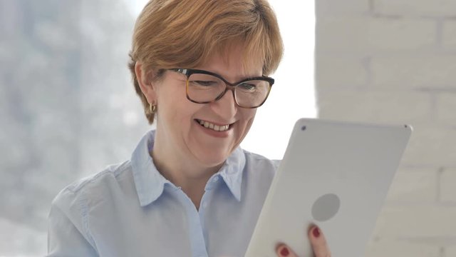Old Woman Using Tablet and Celebrating Success of Project