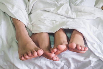 Close up of male and female feet on a bed and couple having sex in the bedroom.