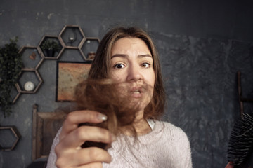 young woman looking on comb with hair, horror and tantrum, hair problems