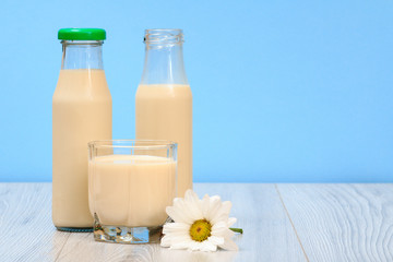 Two bottles and glass of milk in blue background.