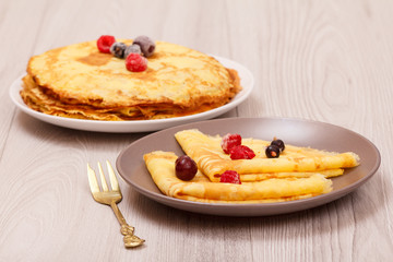 Homemade pancakes on plates and fork on wooden desk.