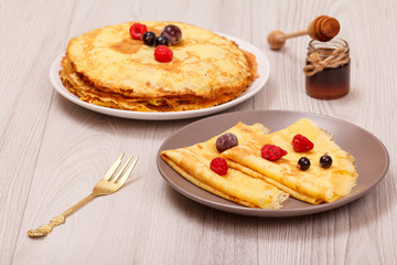 Homemade pancakes on plates and glass bowl with honey