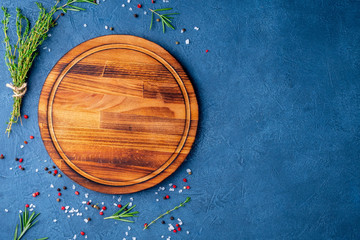 Spices, Herbs and round wooden cutting board on black blue dark concrete backdrop. Top view, copy...
