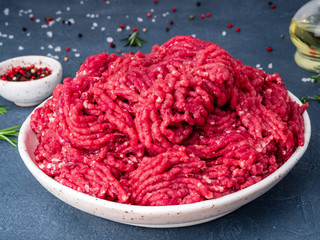 Mince beef, ground meat with ingredients for cooking on dark blue background, side view, close up
