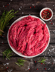 Mince beef, ground meat with ingredients for cooking on old gray dark wooden rustic table, top...