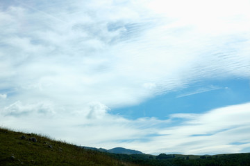 Blue sky and beautiful clouds with meadow tree and mountains Plain landscape background for summer poster Clouds are shaped in a way that changes shape and movement Sky texture and background  