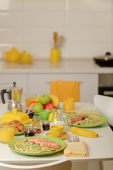 Breakfast time. Omelet with greens and sausages. Croissants and orange juice, jam. Coffee with cream or milk. Fruits - bananas, red and green apples.