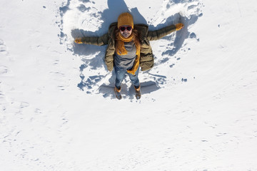 Fototapeta na wymiar The girl is making an angel in the snow.
