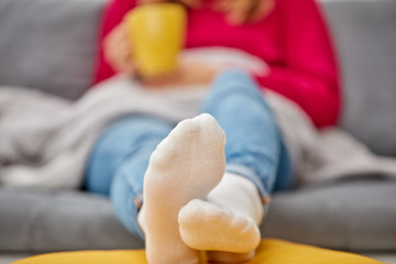Sick girl holding cup and drinking coffee / tea on a couch.