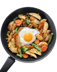 Cooked food: frying pan with cut pieces of fried potatoes, carrots, beans, broccoli and fried egg on white isolated background. Flat lay view directly above