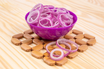 Obraz na płótnie Canvas Slices of.onion. Onion in ceramic bowl on wooden background