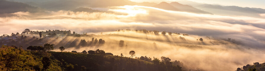 A village surrounded by mountains with foggy morning time and orange sky, beautiful landscape