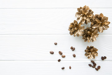 Golden pine cones with coffee beans on white wooden table background, top view, copy space.