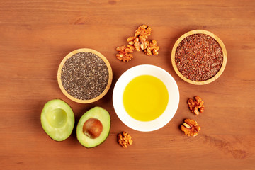 An overhead photo of healthy omega 3 vegan diet food. Avocado, walnuts, chia and flax seeds, shot from the top on a dark rustic background with a place for text