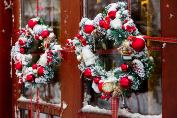 Fototapeta na wymiar Christmas wreath on a door with red decoration, balls and snow