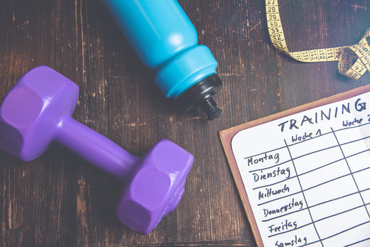 High Angle View Of A Workout Plan In Notebook At Wooden Desk