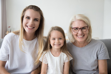 Portrait of three 3 generations family happy old grandmother, smiling young mother and cute preschool child girl looking at camera, kid daughter, mother and aged grandma posing together headshot