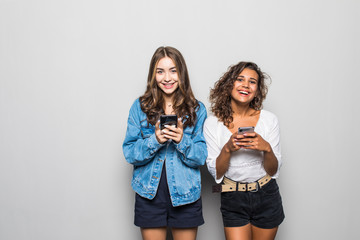 Portrait of happy mixed race two women using mobile phone or internet addicted friends isolated...