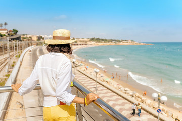 Fototapeta na wymiar Young woman in hat looking at the beach in Tarragona, Costa Dorada