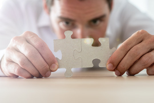 Businessman merging together two matching puzzle pieces