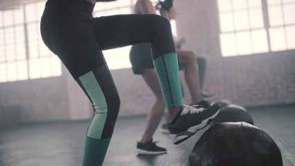 Young women exercising in aerobics class with medicine balls on floor. Three females doing exercise with medicine ball in gym. - Powered by Adobe