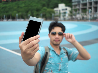 Young Asian tourist taking a photo or selfie. Selective focus and shallow depth of field.