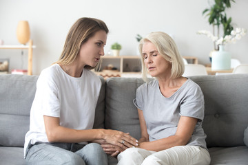 Loving adult daughter talking to sad old mother holding hand comforting upset older woman having problem, young caregiver helping senior patient, support, empathy and care to elderly parent concept - obrazy, fototapety, plakaty
