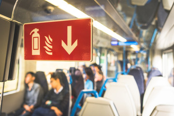 Red fire extinguisher sign sticker on the glass in the underground, train, subway or tube for safety in Europe, UK with a group passengers.