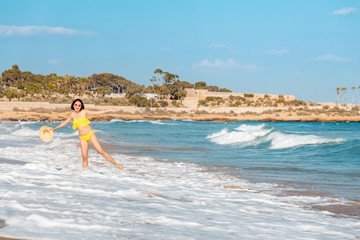 Young woman tourist in swimsuit having fun in wavy waters of Mediterranean sea, storm weather at the sea concept