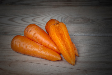 Fresh large carrots lie on a natural wooden background.