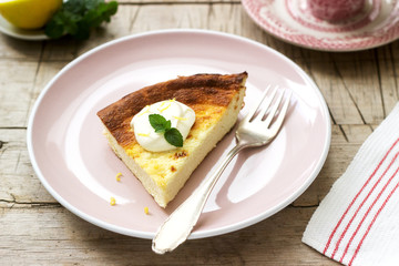 Healthy breakfast made from soft cottage cheese casserole with oatmeal and lemon zest, served with sour cream and mint.