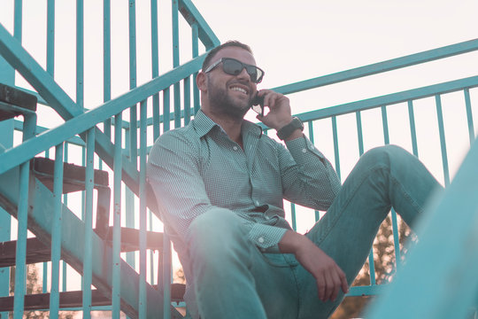 A middle-aged man uses a cell phone outside.A man with sunglasses having conversation over mobile phone outdoor.