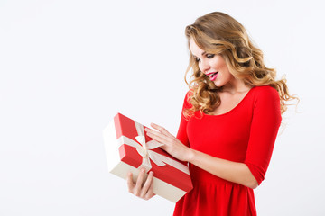 Beautiful cheerful woman in red dress with a gift over white.