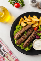 Traditional cevapcici served with baked potatoes. Flat lay. Stone background.