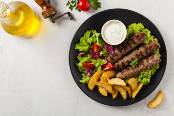 Traditional cevapcici served with baked potatoes. Flat lay. Stone background.