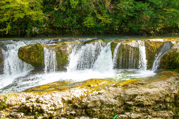 Fototapeta premium Amazing view on waterfall in the picturesque Martvili canyon in Georgia near Kutaisi. Beautiful natural canyon with view of the mountain river, christal blue water and boat ride.