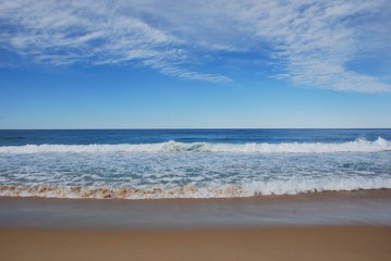 Scenery at the beach shows clean sand and deep blue sea